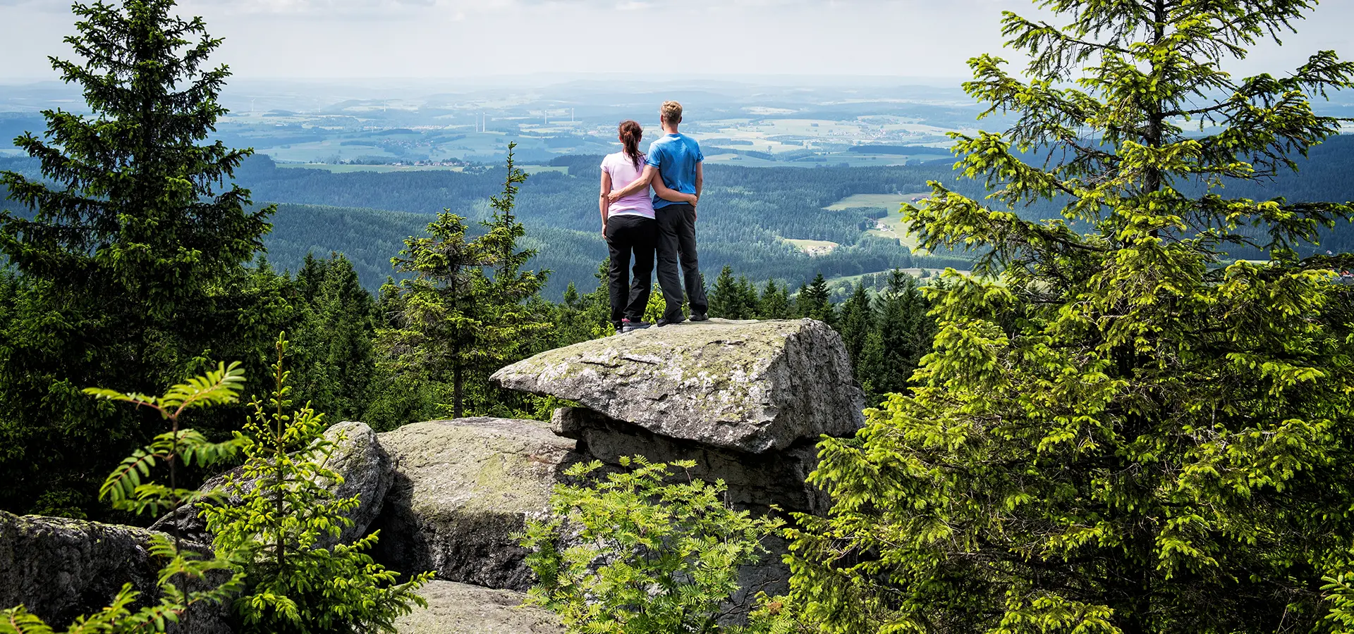Zwei Menschen blicken von einem Felsen auf die Landschaft der Region Bayreuth.